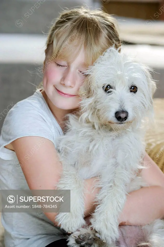 Girl, 9, cuddling with a young mixed-breed dog