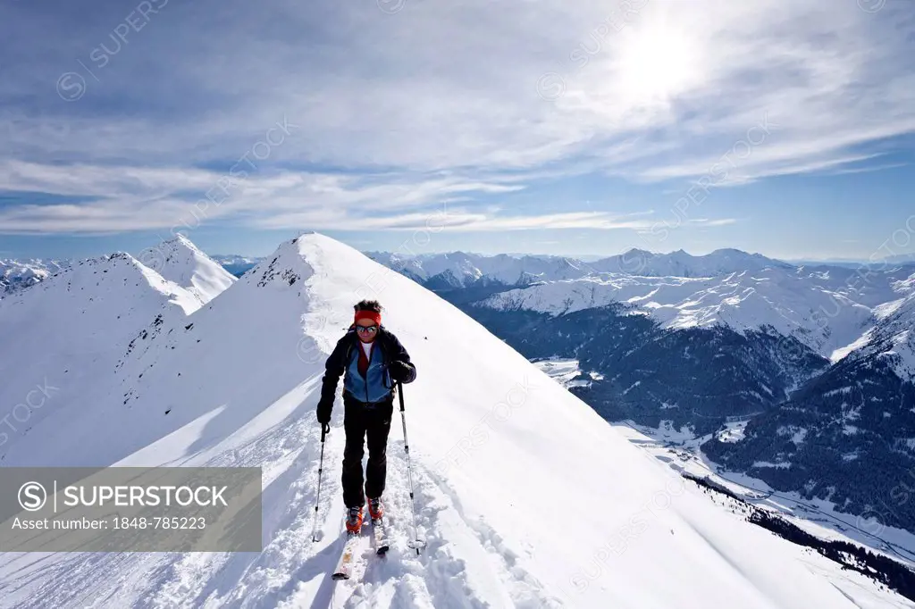 Cross-country skier ascending Ellesspitze Mountain, here on the summit ridge with Ridnauntal Valley below