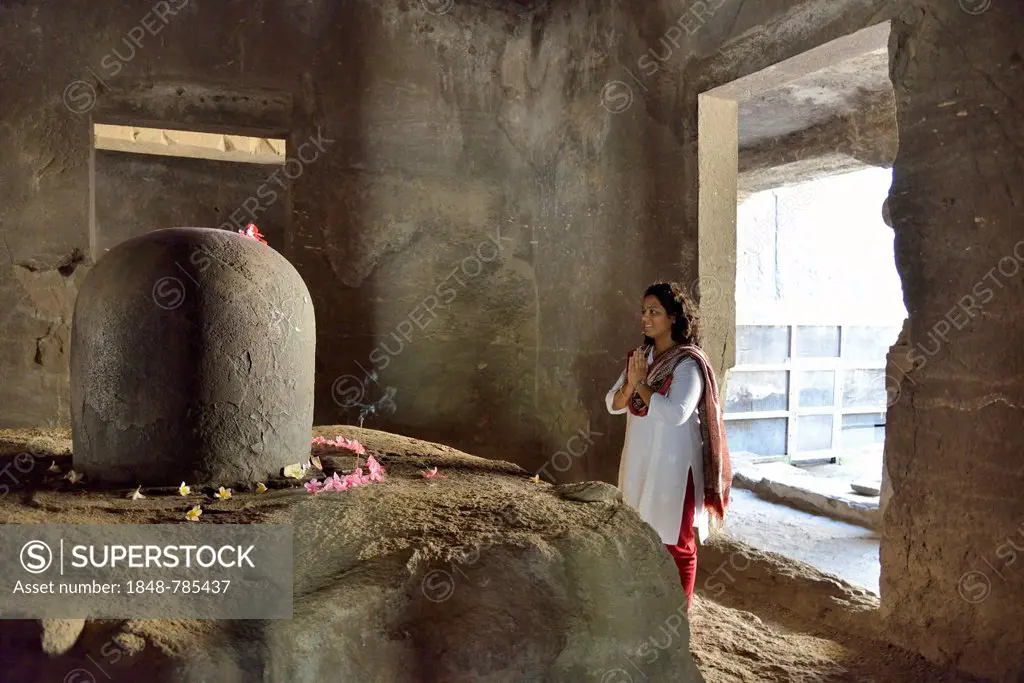 Woman praying in front of the Shiva Lingam, a phallic symbol, in the main cave of the Shiva temple, UNESCO World Heritage Site