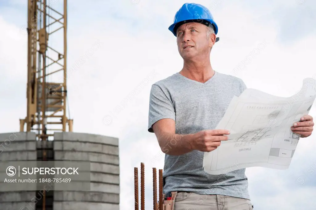 Construction worker wearing a hard hat and holding a building plan