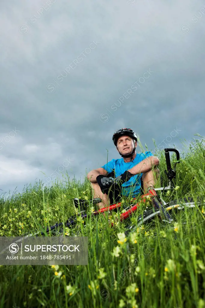 Man sitting with a mountain bike in a meadow
