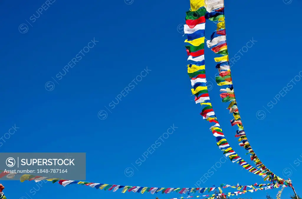 Buddhist prayer flags in front of blue sky above Namche Bazar (3.440 m), the base for trekking and mountaineering in Solo Khumbu region