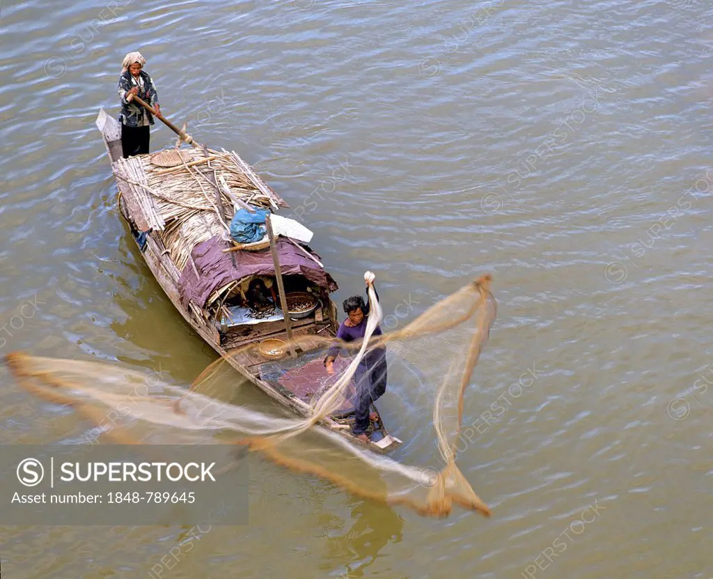 Fisherman casting his net, fishing boat on the Tonle Sap River