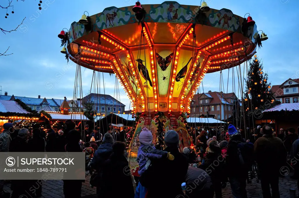 Children's carousel at the Christmas market on Schlossplatz square, with visitors at the front at dusk