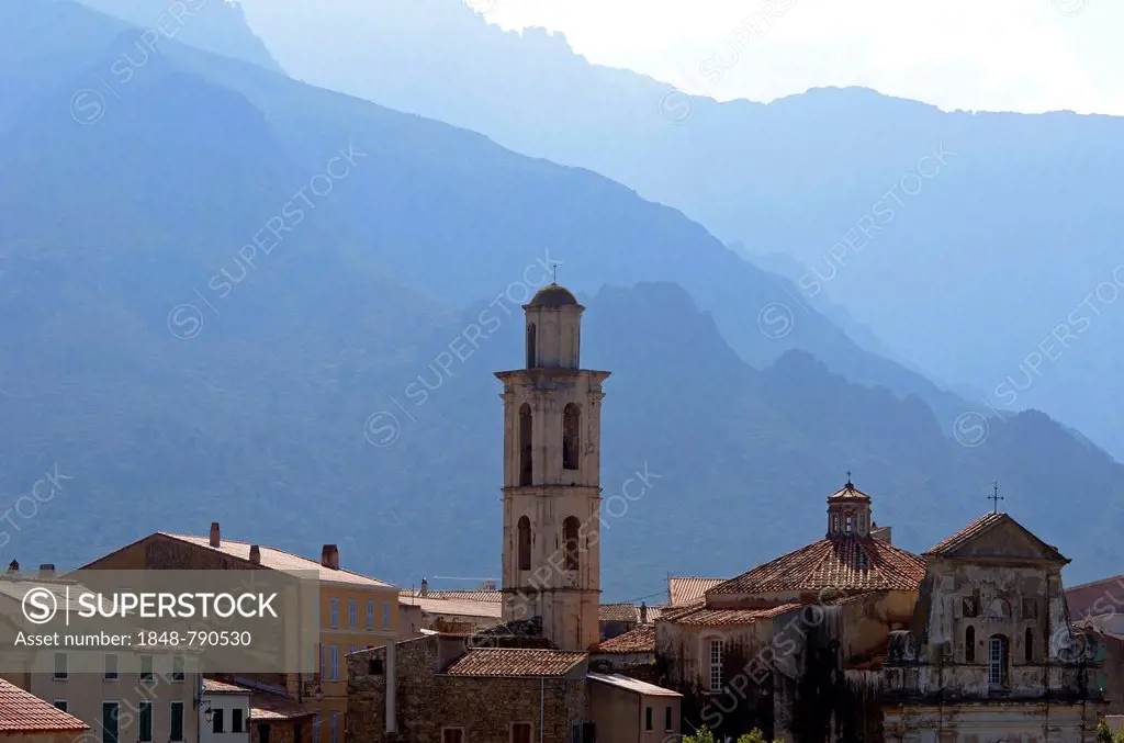 The village of Montemaggiore dominated by the tower of its church in front of the steep mountains of Corsica