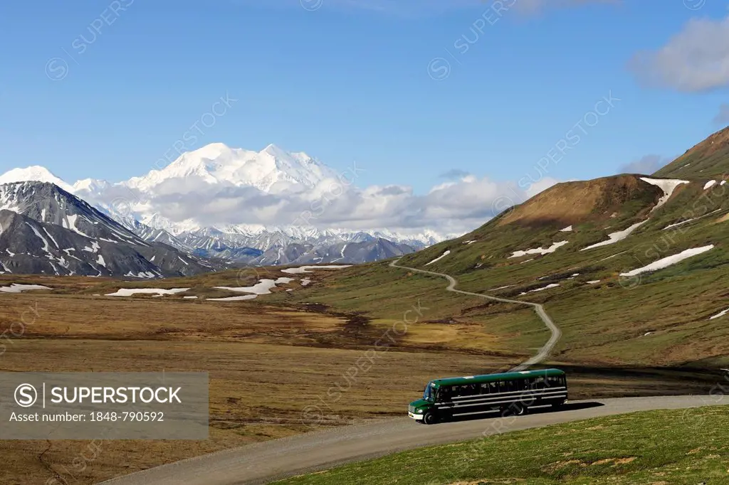 A shuttle bus crossing the Denali National Park and Preserve with views of Mt McKinley at back
