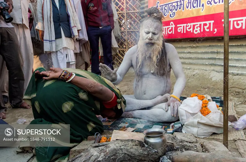 Shiva sadhu from Avahan Akhara, holy man, blessing a pilgrim at the Sangam, the confluence of the rivers Ganges, Yamuna and Saraswati, during Kumbha M...