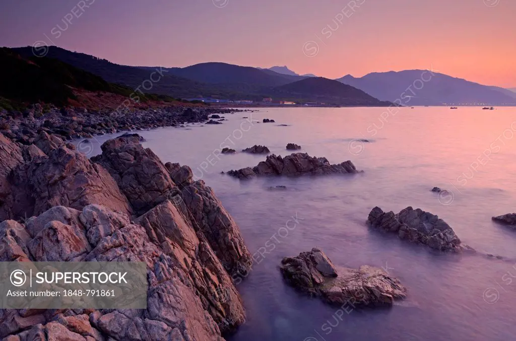 Sunrise behind the mountains of Corsica near Ajaccio with the rocky mediterranean coast on the foreground. Ajaccio is the capital of the mediterranean...