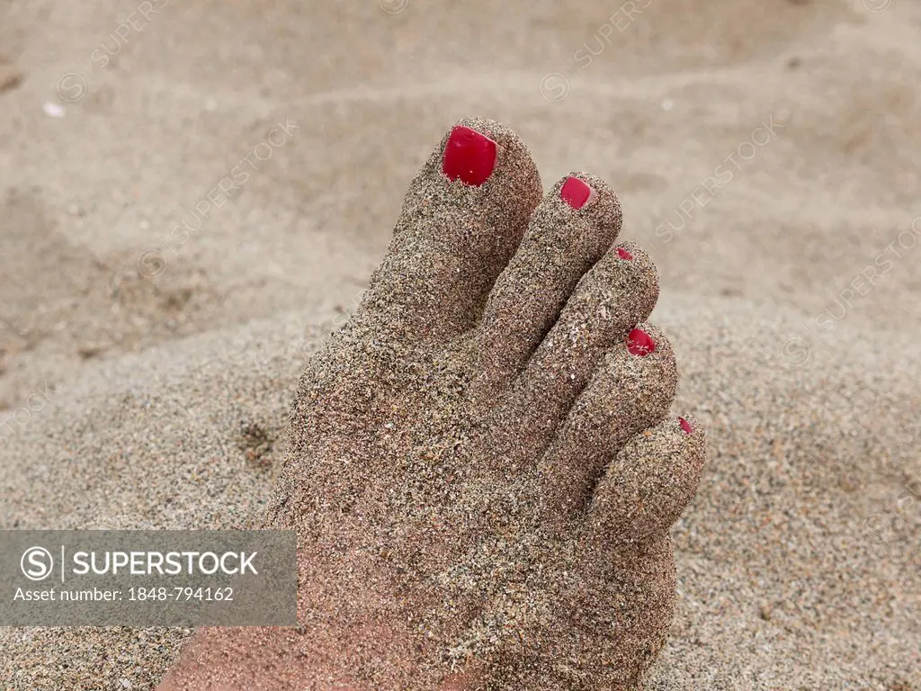 Sand-covered food with painted nails on the beach