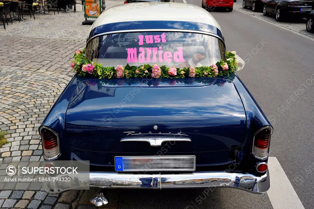 Blue Opel Rekord P1 car, in use as a wedding car, with the lettering just married in the rear window