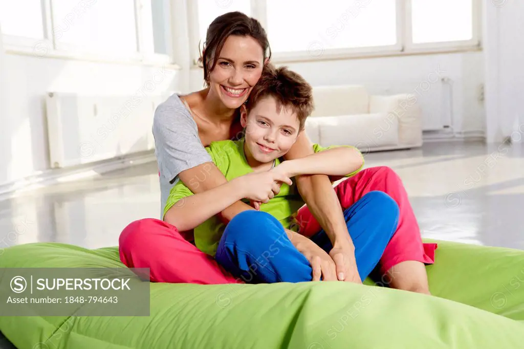 Mother and son in casual clothes sitting on a beanbag in a loft