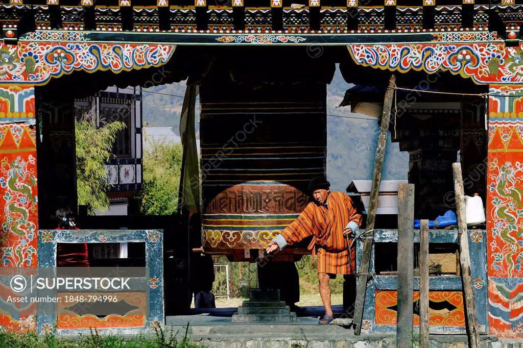Man turning the large prayer wheel in the town centre of Mongar