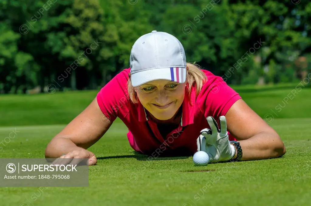 Female golfer flicking the golf ball with her fingers into the hole, Golfclub Schloss Myllendonk