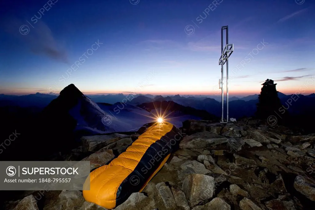 Mountain climber sleeping on the summit of Wilder Pfaff Mountain, bivouac at the summit cross