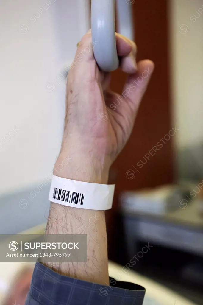 Senior with a barcode wristband in a hospital, detail of a hand holding a hand grip on a bed