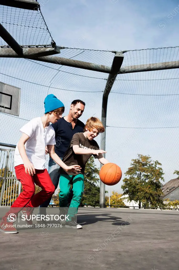 Two cool boys playing basketball with their father