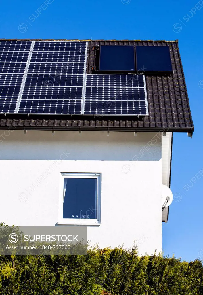 Roof of a residential house with solar panels to generate electricity and solar thermal panels for hot water
