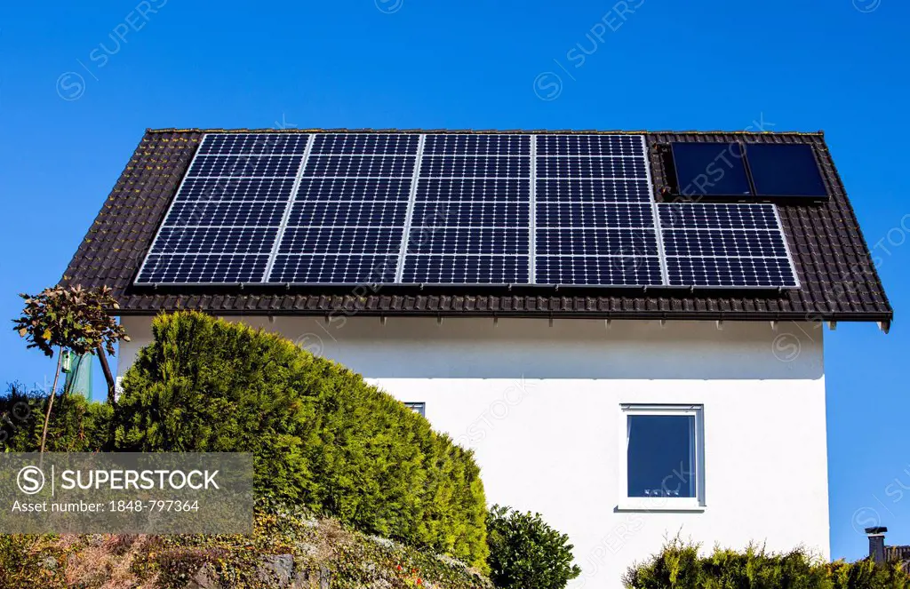 Roof of a residential house with solar panels to generate electricity and solar thermal panels for hot water