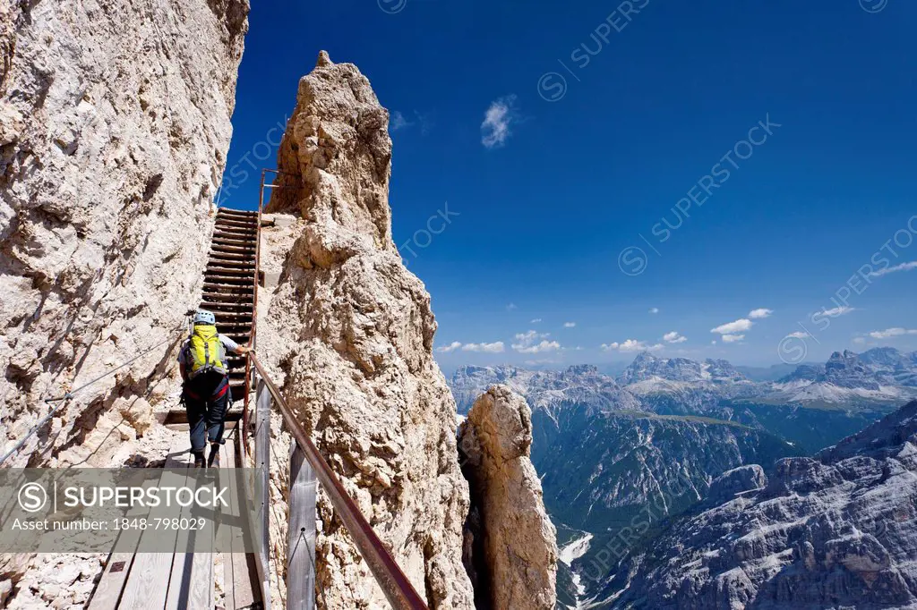 Hiker climbing Monte Cristallino mountain, here on the Ivano Dibona fixed rope route on Cristallo mountain above Cortina, Belluno, Dolomites, Italy, E...