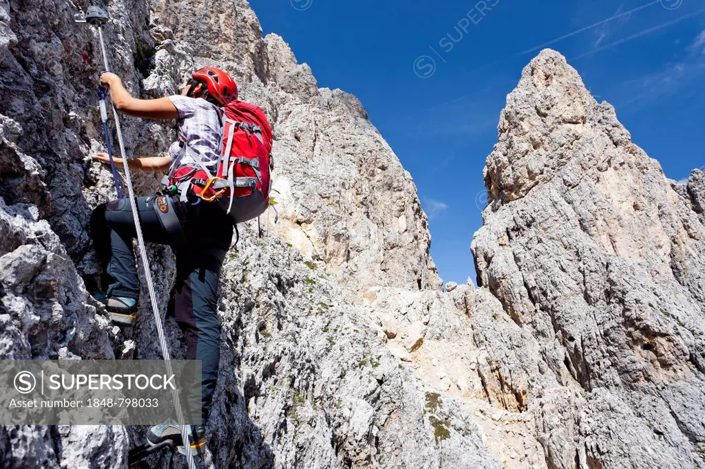 Hiker climbing to the summit of Plattkofel mountain, here on the Oskar Schuster Stieg trail, fixed rope route, Dolomites, province of Bolzano-Bozen, I...