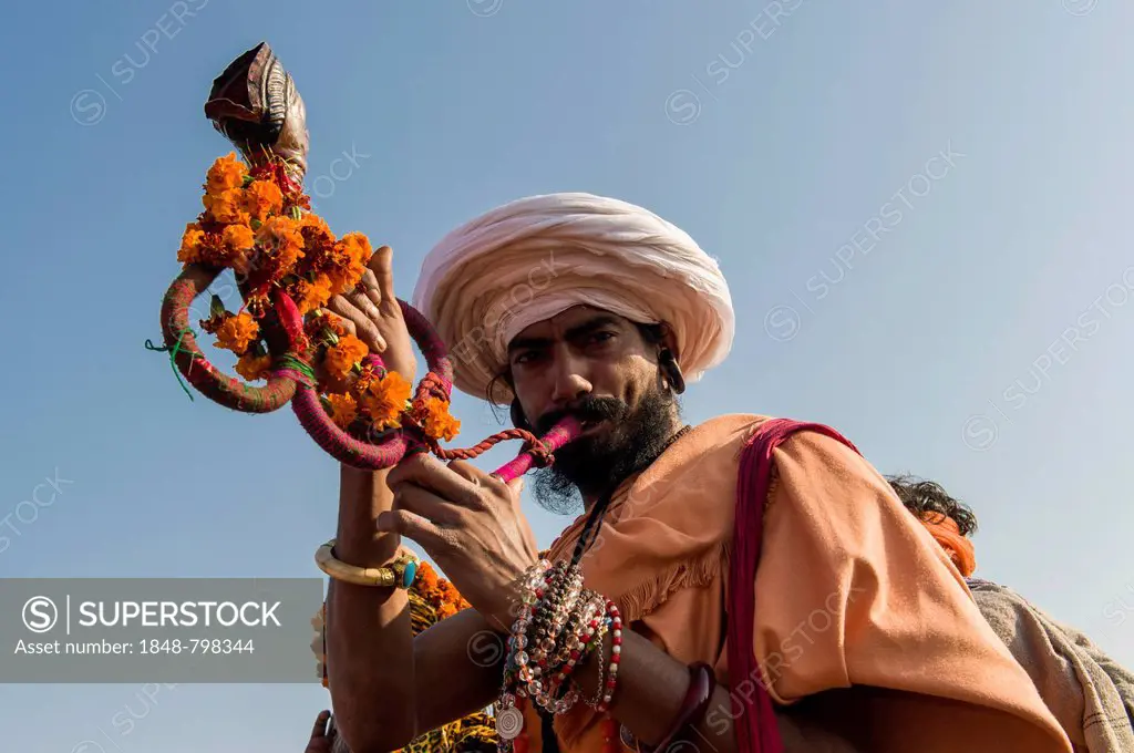 Sadhu, holy man, blowing the signal for Shahi Snan, the royal bath, during Kumbha Mela festival