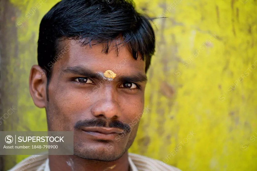 Man in front of lemon-yellow wall with bindi on his forehead, portrait, Meenakshi Amman Temple or Sri Meenakshi Sundareswarar Temple