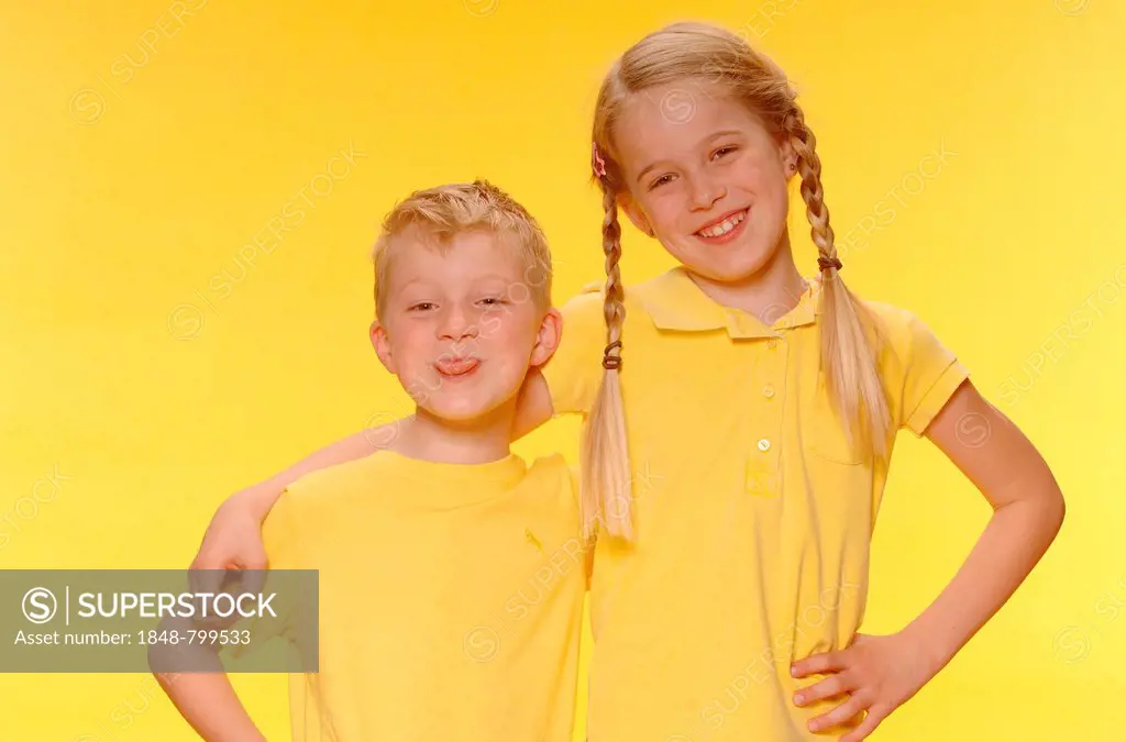 Boy and girl, brother and sister, standing arm in arm, smiling