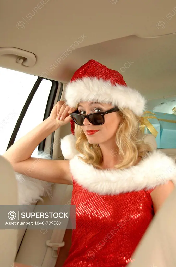 Sexy female Santa with sunglasses sitting in a car