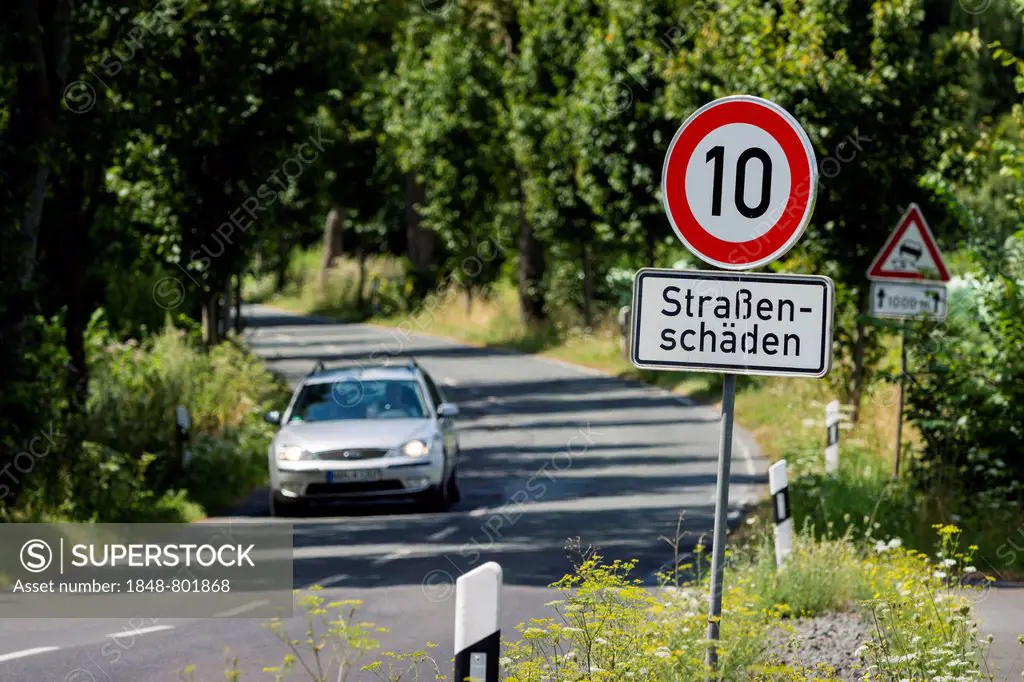 A car travelling on the L657 road, speed limit sign of 10km h, due to road damage, Mengede, Dortmund, Ruhr district, North Rhine-Westphalia, Germany