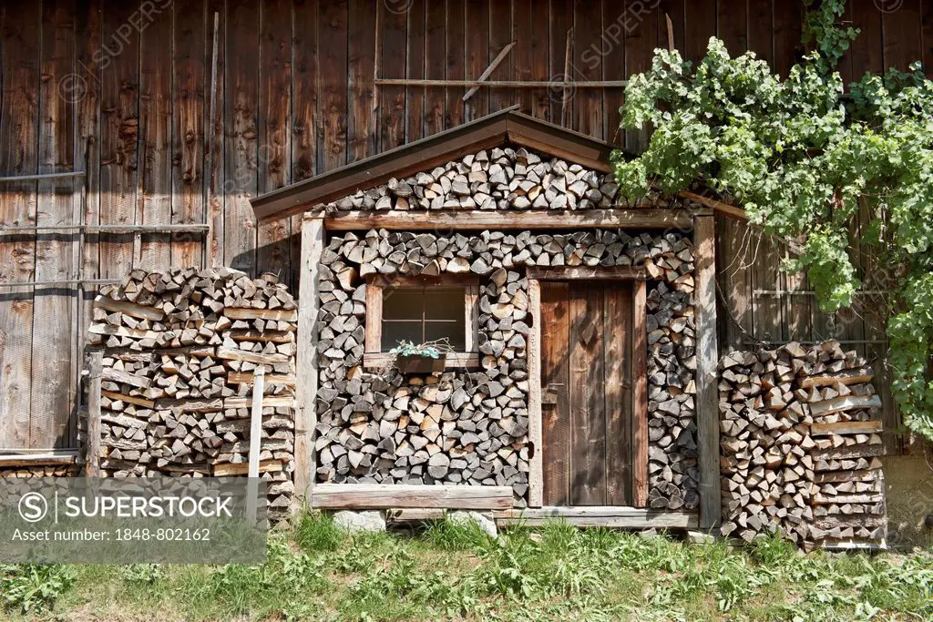Stack of firewood in the shape of a log cabin with a rustic front door, roof and window, Ammerland am Starnberger See, Münsing, Upper Bavaria, Bavaria...