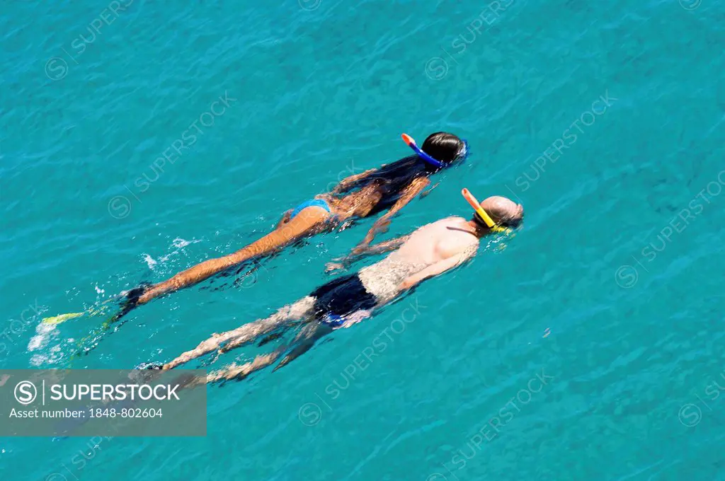 Swimming couple, a man and a woman swim with snorkel and fins in turquoise water of the mediterranean sea, Greece.