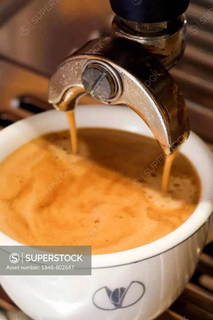 A cup of coffee is prepared with an espresso machine
