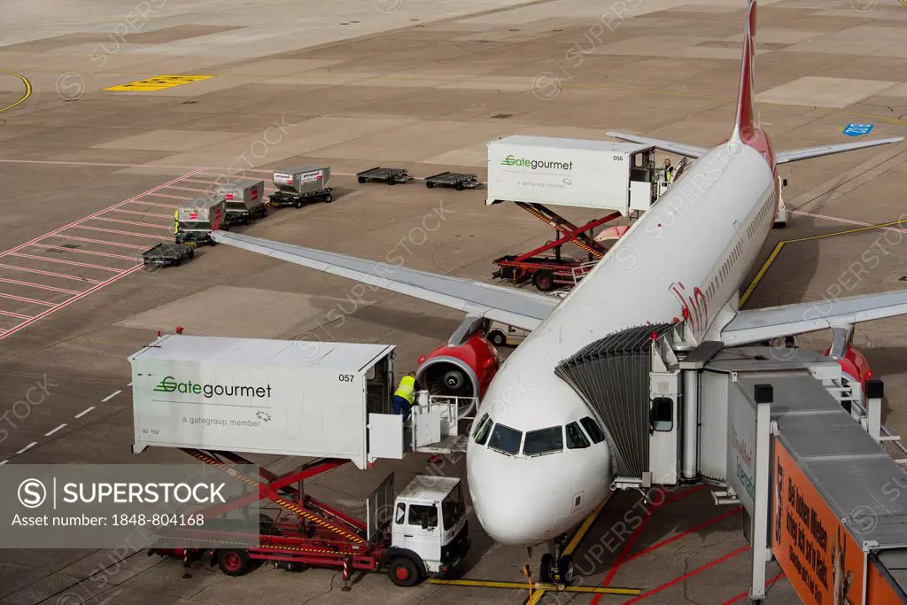 Aircraft is being prepared for the flight, elevating platform truck delivering goods for the galley, baggage car and airplane gangway attached to the ...