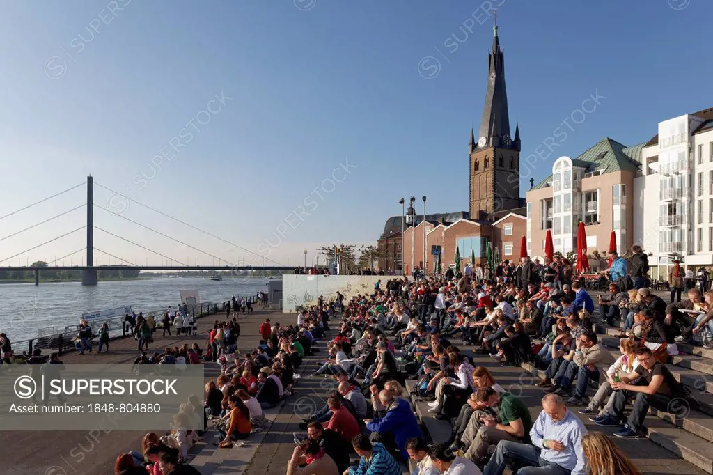 People sitting on a flight of steps in the evening sun, Burgplatz square with St Lambertus church, historic center, Düsseldorf, Rhineland, North Rhine...