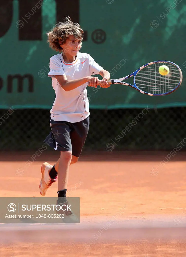 Boy, 10, playing tennis, hitting with a two-handed backhand, Munich, Upper Bavaria, Bavaria, Germany
