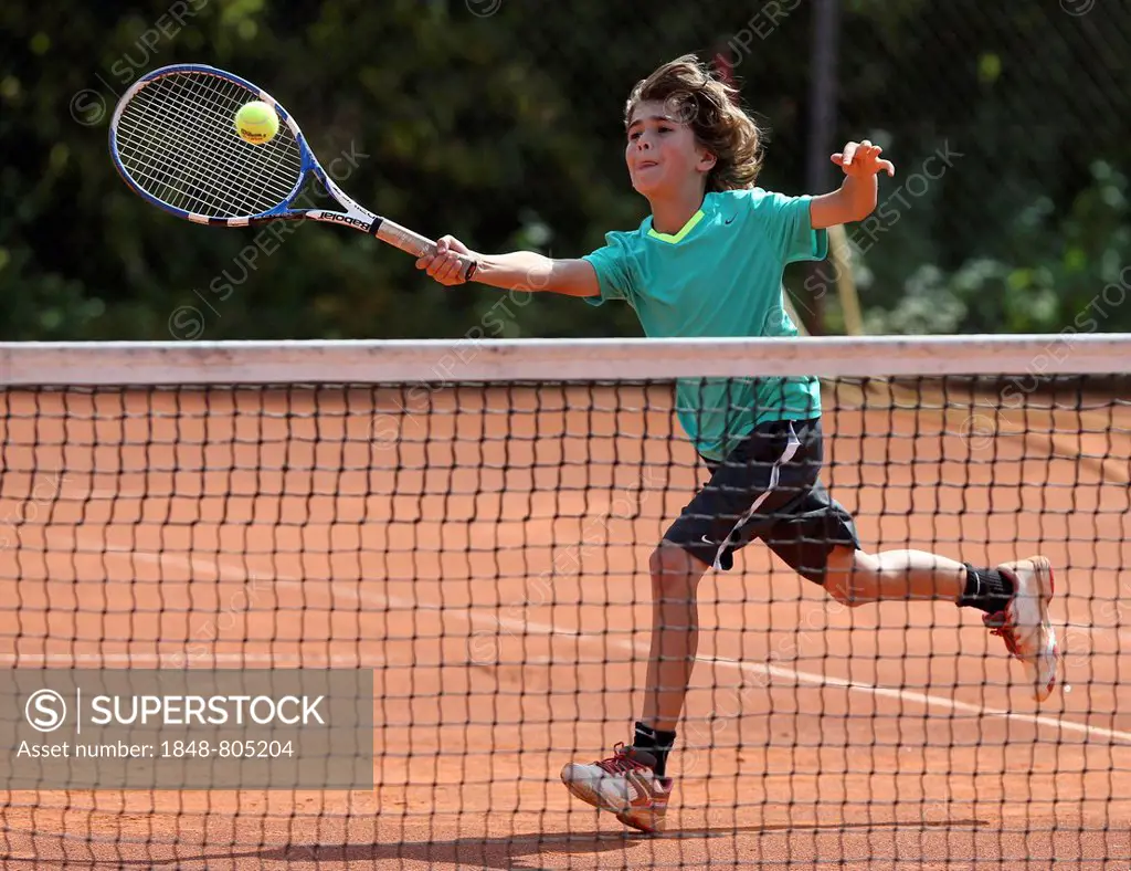 Boy, 10, playing tennis, hitting a forehand volley, Munich, Upper Bavaria, Bavaria, Germany