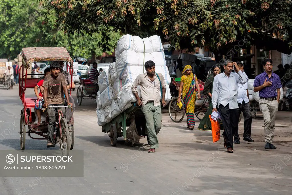 A cycle rickshaw and a man transporting goods on a hand cart on Khari Baoli Road, Old Delhi, New Delhi, Delhi, India