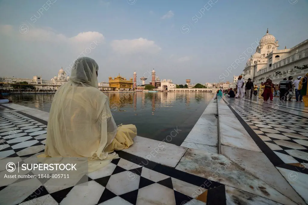 A Sikh devotee sitting at the holy pool, Harmandir Sahib or Golden Temple, a holy Sikh temple, Amritsar, Punjab, India