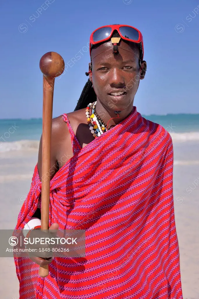 Young Maasai man wearing traditional dress and sunglasses on the beach, Dongwe Beach, Dongwe, Zanzibar, Tanzania