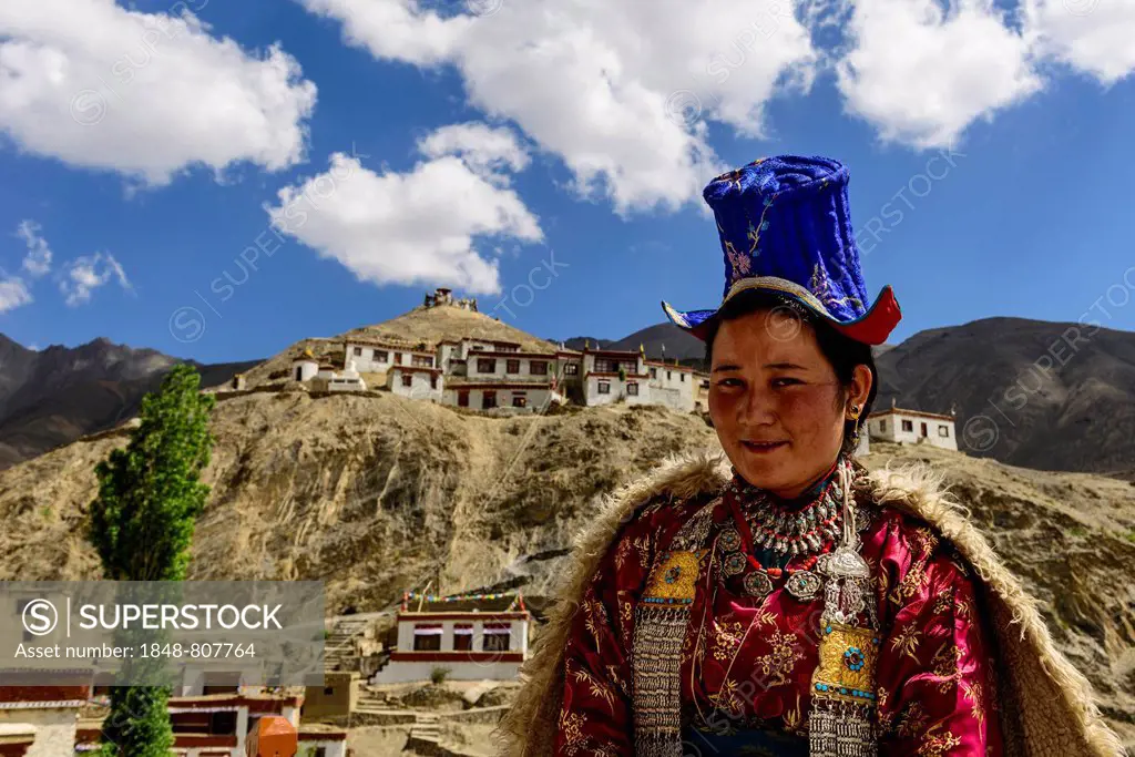 Ladakhi woman wearing traditional dress, Lamayuru Gompa at back, Lamayuru, Ladakh, Jammu and Kashmir, India