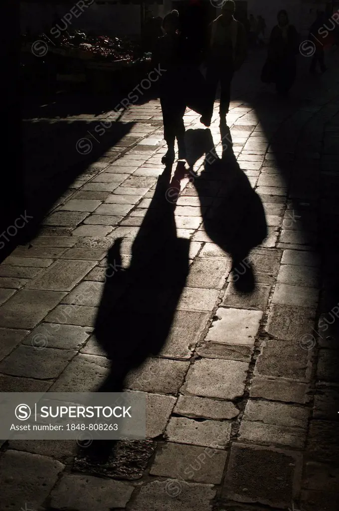 Pedestrians casting long shadows on the historic sidewalk, Venice, Venezien, Italy