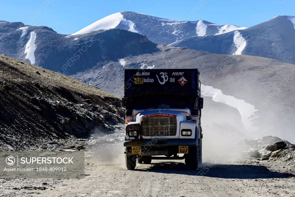 A truck driving on the dusty winding road leading up to Taglang La, 5.325 m, the highest pass on the Manali-Leh Highway, snow covered mountains in the...