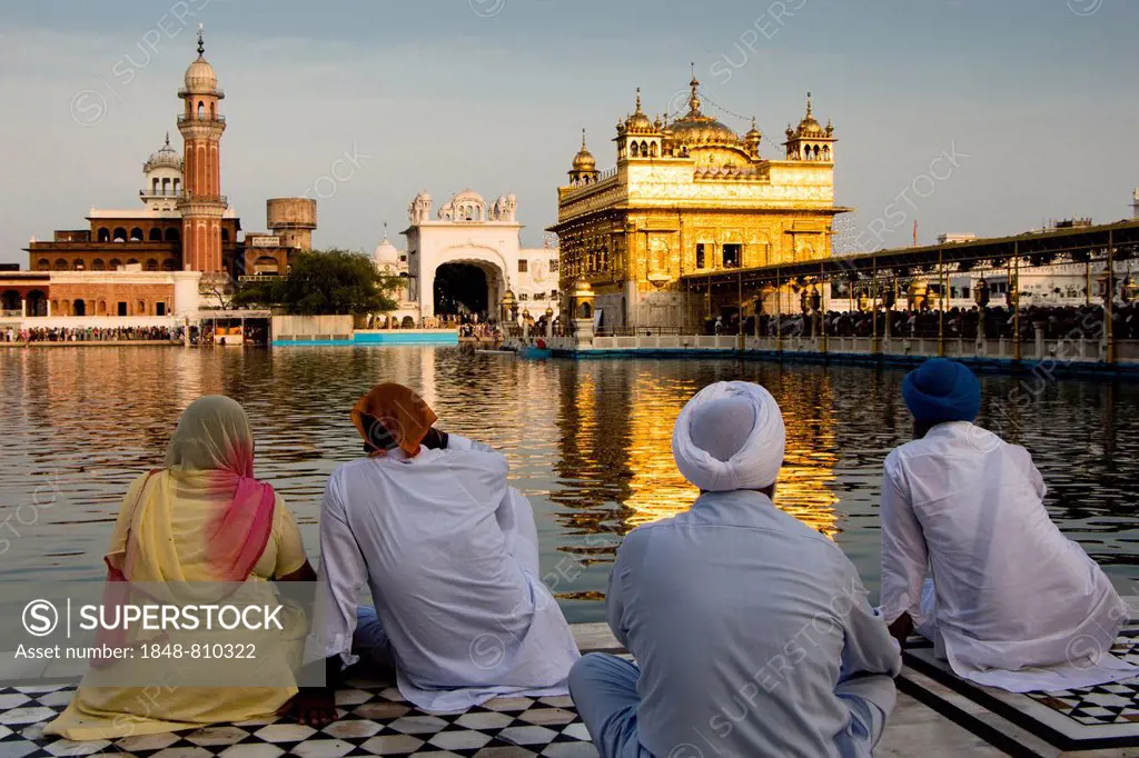 Sikh pilgrims sitting in front of the Harmandir Sahib or Golden Temple, Amritsar, Punjab, India