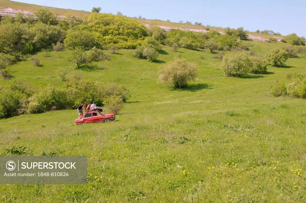 Small red car, Zaporozhets, driving across a meadow, Crimean Mountains, Crimea, Ukraine