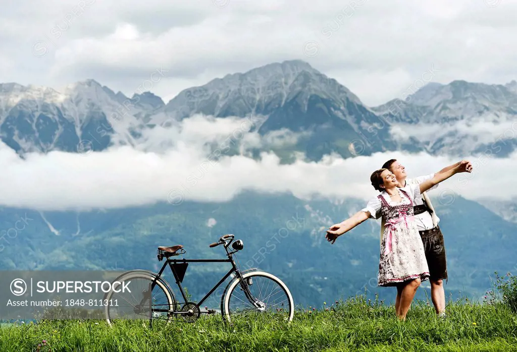 Man and a woman wearing traditional costume with an old bicycle within a natural landscape, Aldrans, Tirol, Österreich, Tyrol, Austria