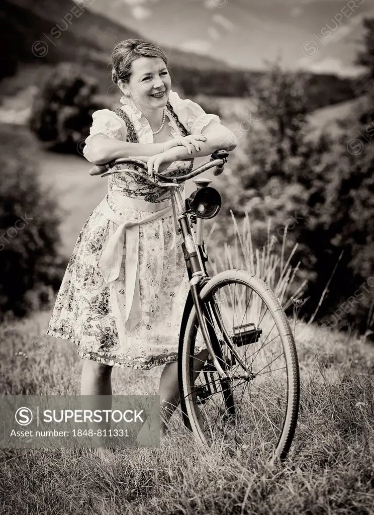 Woman wearing a dirndl with an old bicycle, Igls, Innsbruck, Tyrol, Austria