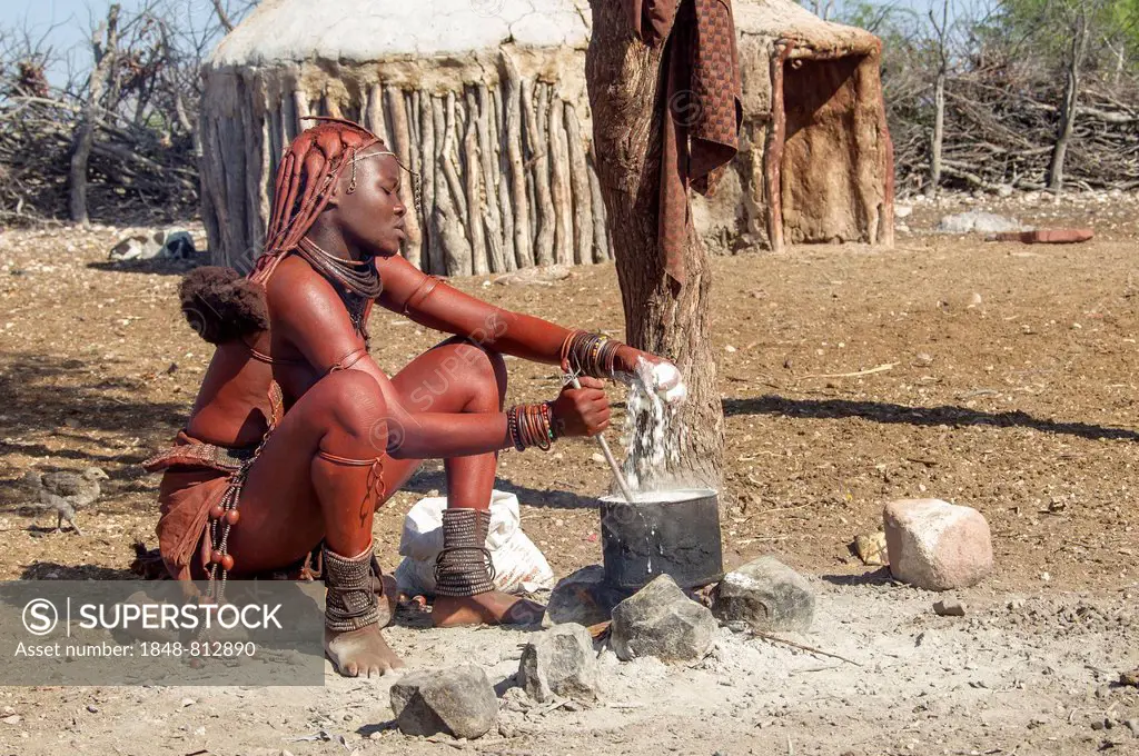 Young Himba woman, sitting at a cooking pit in front of a hut, Kaokoland, Kunene, Namibia