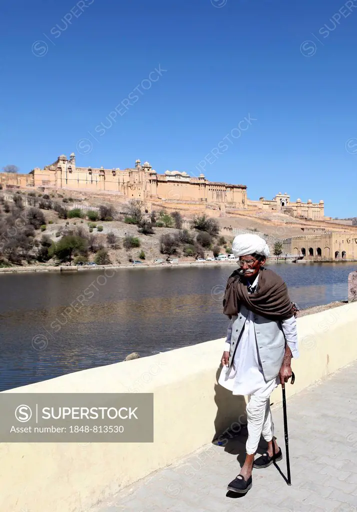 Man with turban walking on the sidewalk, Amer Fort behind, Amber, Jaipur, Rajasthan, India