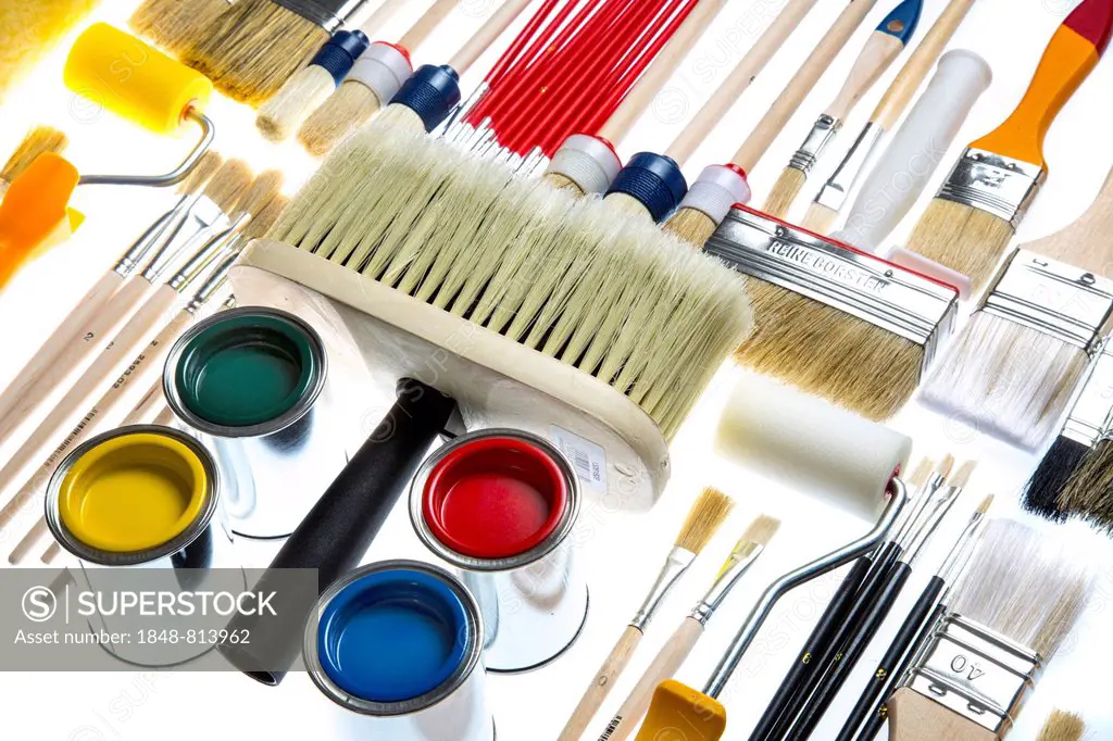Different types of brushes, paint rollers and cans of paint