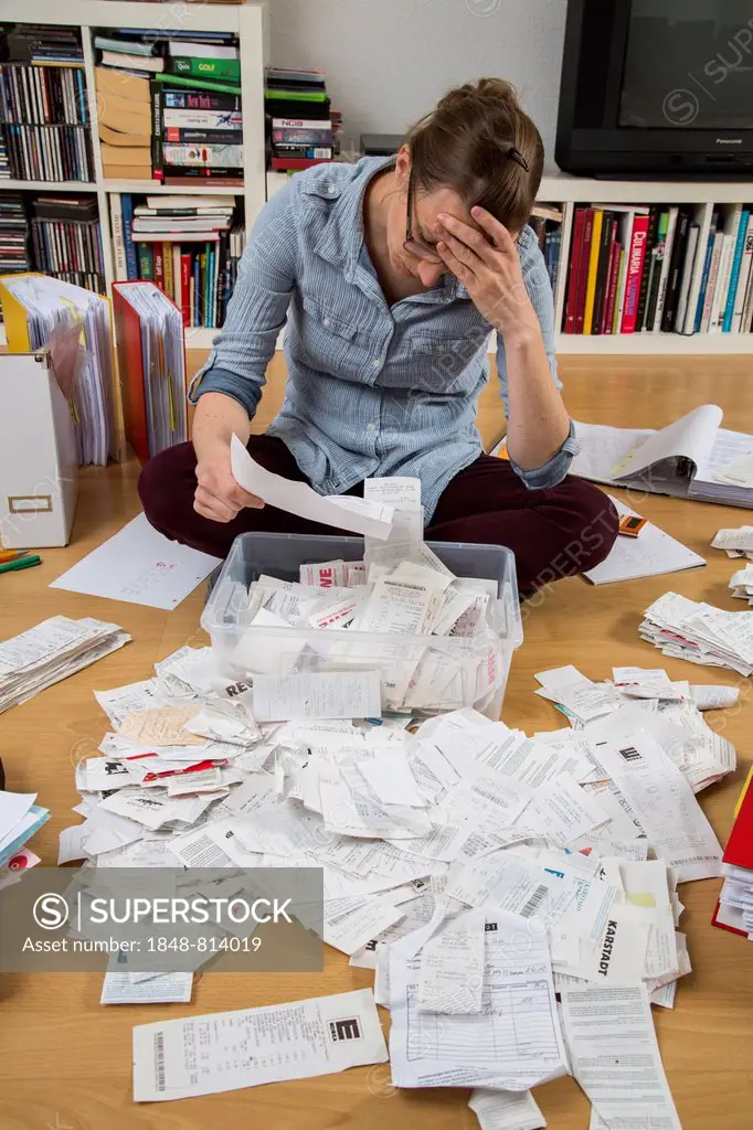 Woman sorting documents, records, invoices and receipts on the ground, for the tax return